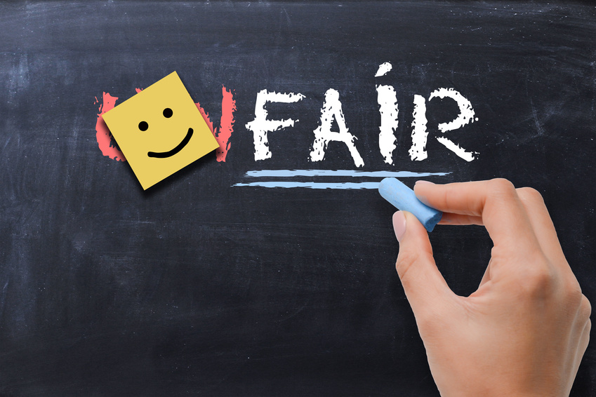 Woman transforming the word unfair to the word fair on blackboard